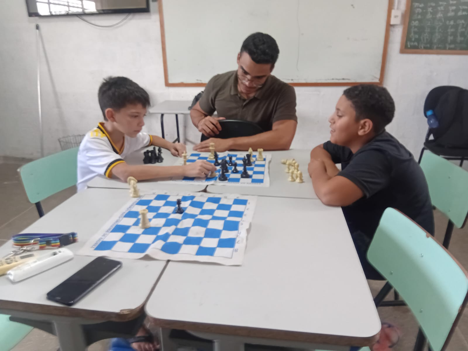 Crianças jogando xadrez com o professor
